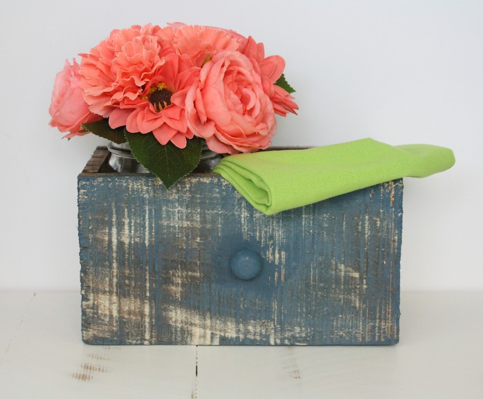 A weathered drawer with bright coral flowers